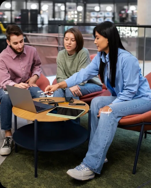 A group of three individuals engaged in discussion at a table with a laptop, displayed on the Rankupper home page.