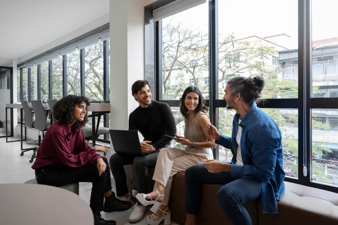 Four team members from Rankupper sitting together on a couch in an office, engaged in discussion.