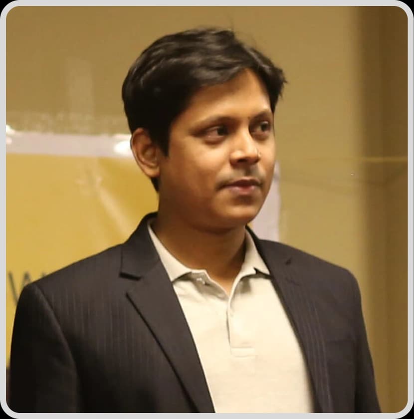 A suited man poses in front of a banner, showcasing his role as Digital Marketing Manager Abdullah Allamin Rankupper.