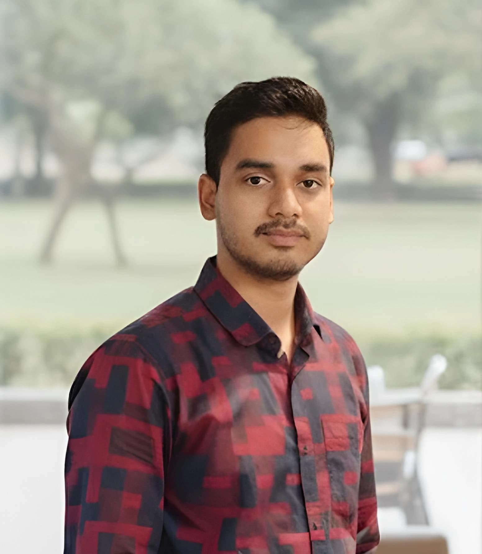 A man in a blue shirt stands with arms crossed, representing Chandan Sarker, Ecommerce Specialist at Rankupper.