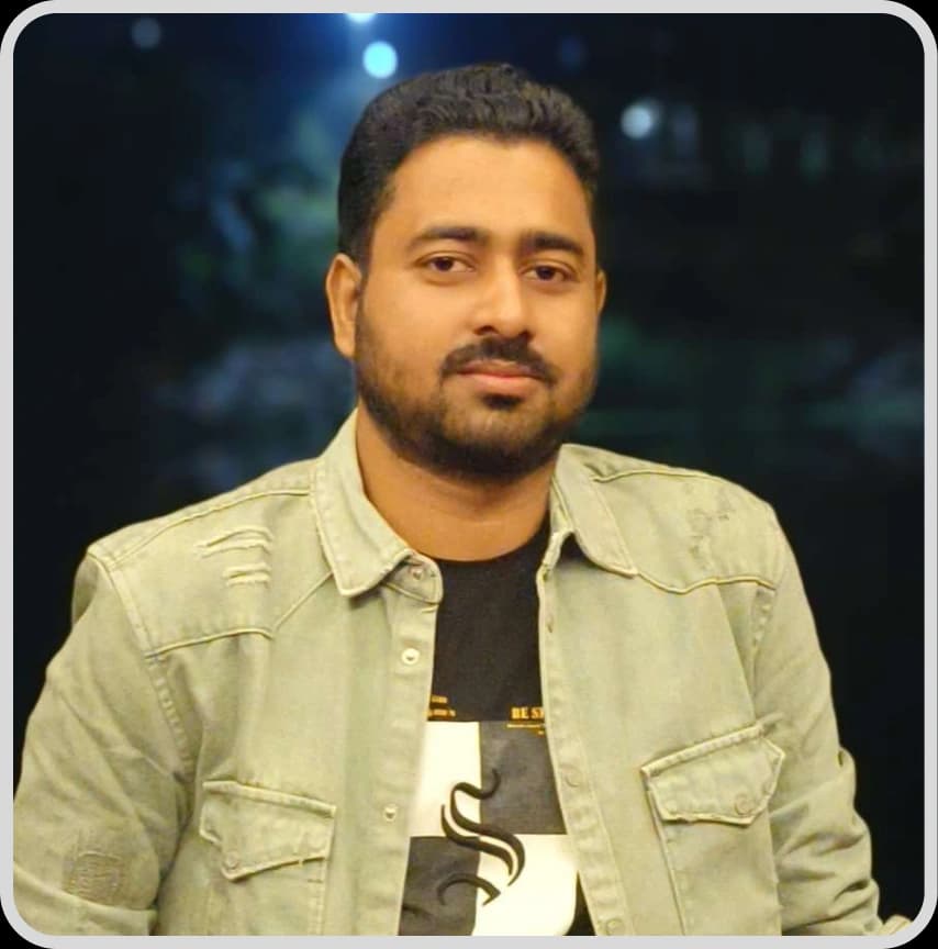 A man in a blue shirt stands with arms crossed, representing Shuvo Gosh, Web Developer at Rankupper.